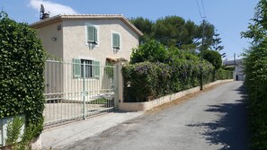 A narrow road flanked by houses with a metal gate and green shutters. - Large studio in a Provençal house (Cagnes-sur-Mer)