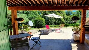 A covered patio area with outdoor furniture, including a table and chairs, and a hanging chair. - Large studio in a Provençal house (Cagnes-sur-Mer)