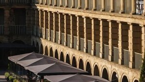 Une cour avec des sièges en plein air et un bâtiment orné de colonnes.