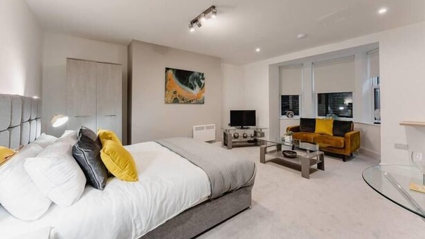 Une chambre moderne avec un grand lit, une télévision, un canapé et une table basse en verre.