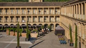 Une cour intérieure avec une haute tour à sommet pointu et un bâtiment doté de nombreuses arcades et de colonnes.