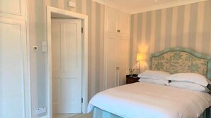 A bedroom with a bed, a nightstand, and a door. - The Garden Apartment - (Filey)
