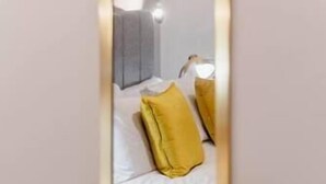 A mirror reflecting a room with a bed, pillows, and a plant. - Apt 3 Prescott Court Halifax (Halifax)