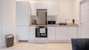 A compact kitchen with white cabinets, a microwave, an oven, and a sink. - Apt 3 Prescott Court Halifax (Halifax)