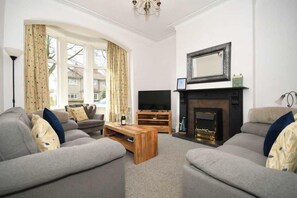 Een woonkamer met een open haard, een televisie en een zithoek.