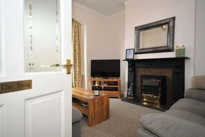 A living room with a television, a fireplace, and a bench.