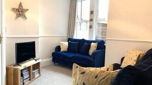 A living room with a blue sofa, a television on a wooden stand, and a star decoration on the wall. - Jackson Landing  - Spacious house with central location (Filey)
