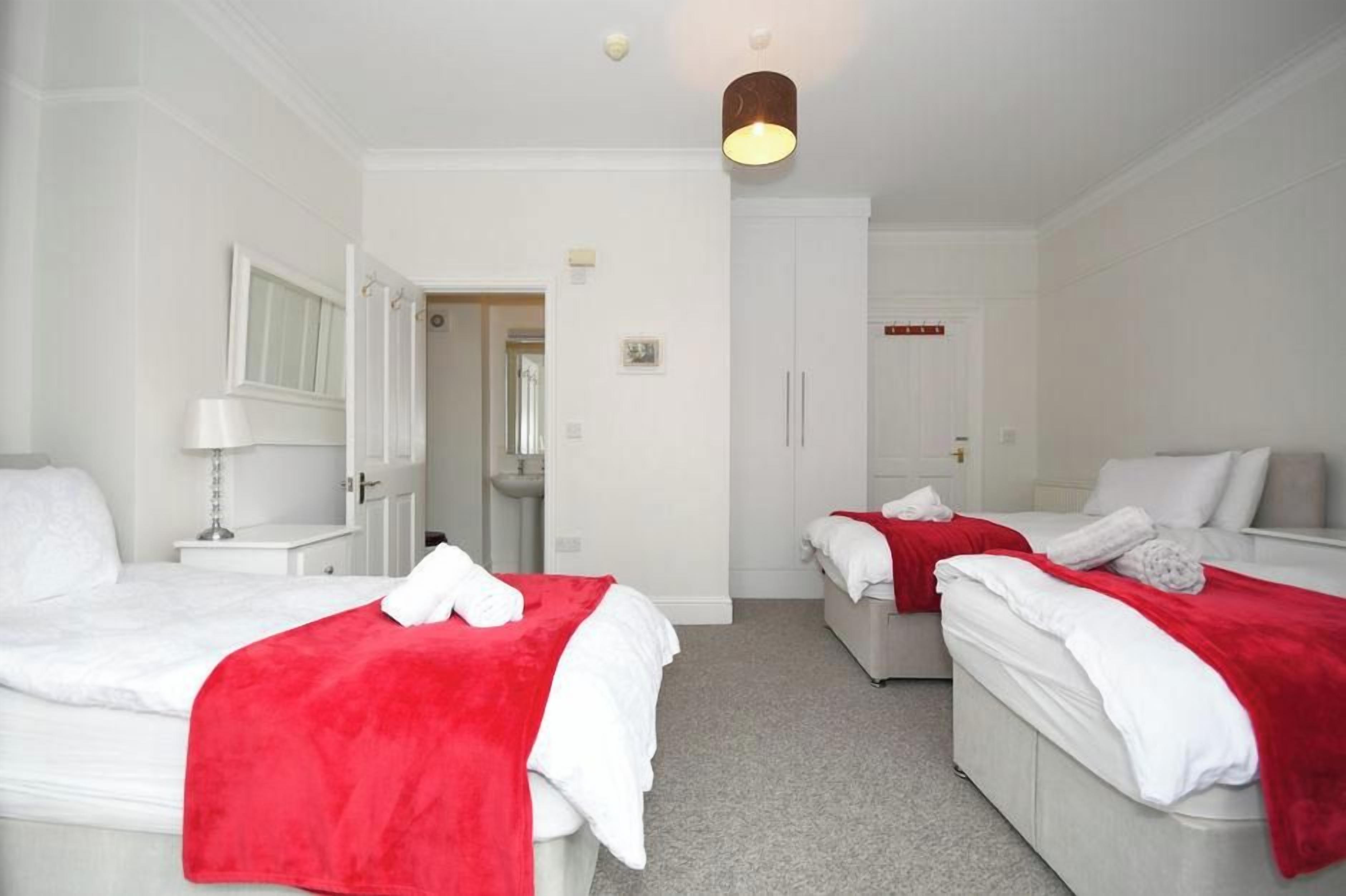 A hotel room with two beds, a bathroom, and a hallway.