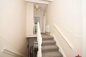 A carpeted staircase with white handrails and a door at the top.