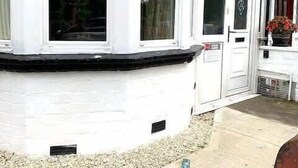A corner of a building with white exterior walls, a black window frame, and a door with a small window. - Jackson Landing  - Spacious house with central location (Filey)