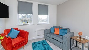A modern living room with a red and grey sofa set, a teal rug, and a small wooden side table. - Apt 8 Prescott Court Halifax (Halifax)