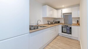 Une cuisine moderne avec des meubles blancs, un évier en acier inoxydable, un four à micro-ondes et un four traditionnel.