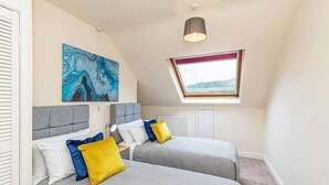 Quarto com duas camas, um claraboia, um quadro e uma luminária de teto.