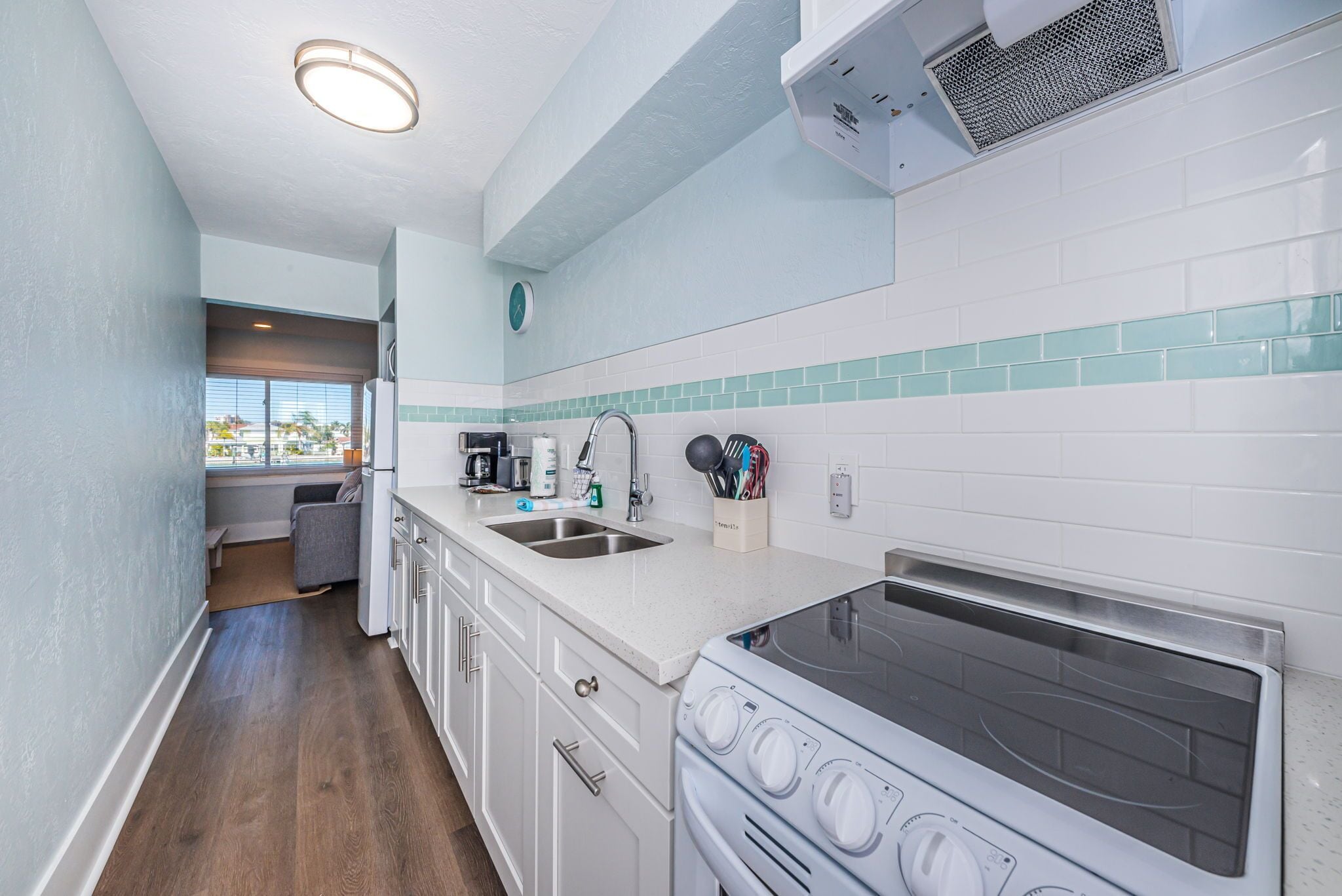 A modern kitchen with white cabinets, a stainless steel stove, and a window overlooking a balcony.