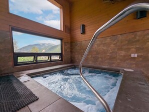Un bain à remous avec vue sur les montagnes, des murs en bois et une fenêtre.
