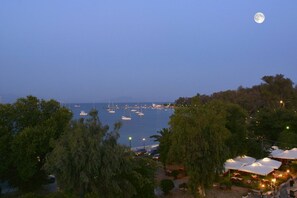 A marina with boats, a moon in the sky, and outdoor seating areas.