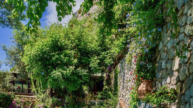 A swimming pool with a stone wall and lush greenery. - VILLA OASI - Four Bedroom Villa, Sleeps 8 (Positano)