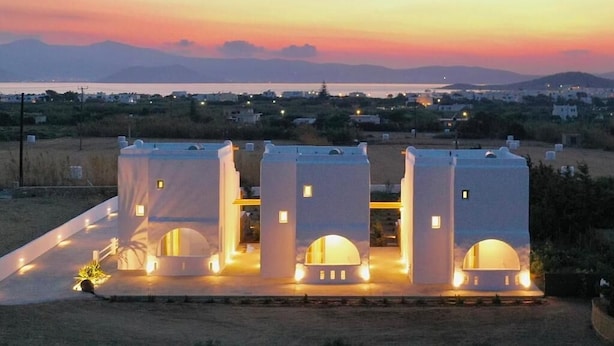 Un edificio moderno con tre torri, ciascuna dotata di una finestra circolare, sullo sfondo di un tramonto.
