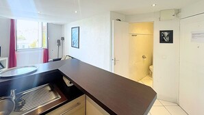 Eine moderne Küche mit dunkler Arbeitsplatte, integriertem Herd und einem Fenster mit Vorhängen.