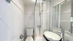 Ein modernes Badezimmer mit einer gläsernen Duschkabine, einer weißen Toilette und einem Waschbecken mit Spiegel darüber.