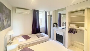Ein Schlafzimmer mit zwei Betten, einem Kleiderschrank, einem Kamin und einer Klimaanlage.