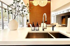 Cozinha moderna com bancada branca, um vaso grande e duas garrafas de vinho.