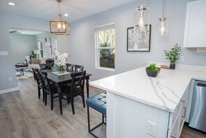A modern kitchen with white marble countertops, a central island, and pendant lighting. - Adorable 4BR 2BA Close to Riverwalk and Downtown (San Antonio)