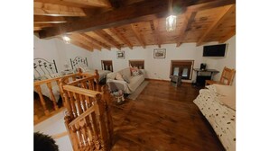 Una habitación con piso de madera, una cama, un sofá y una pequeña mesa.