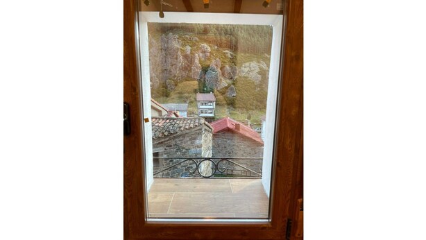 Una puerta de madera con vistas a un edificio de piedra y una estructura de techo rojo.