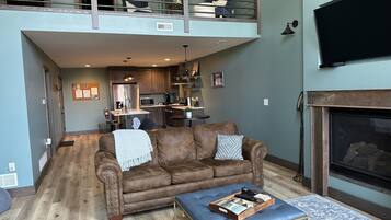 A spacious living area with a brown leather sofa, a coffee table, and a fireplace.
