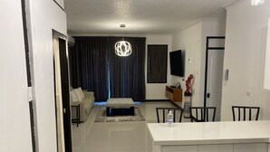 A modern living room with a sofa, ottoman, and a dining area with chairs and a table.