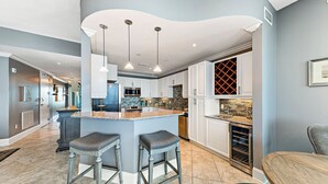 Een moderne keuken met een centraal eiland, barstoelen en hanglampen.