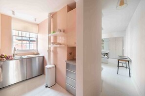 A modern kitchen with stainless steel appliances, a window, and a white trash bin.