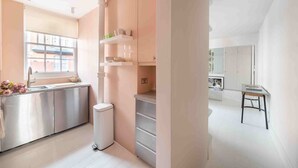 A modern kitchen with stainless steel appliances, a window, and a dining area with a table and chairs. - Open plan Chelsea apt for 2 nr King’s Road (London)
