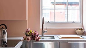 A kitchen with a stainless steel sink, a kettle, and a bouquet of flowers on the counter. - Open plan Chelsea apt for 2 nr King’s Road (London)