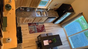 A kitchen with wooden cabinets, a granite countertop, a double sink, and a window overlooking greenery.