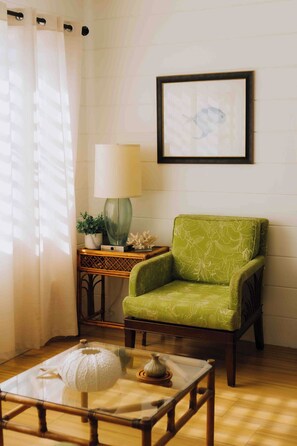 A room with a green armchair, a table with a white object, a lamp, and a framed picture on the wall. - Island View Guesthouse (St. Thomas)