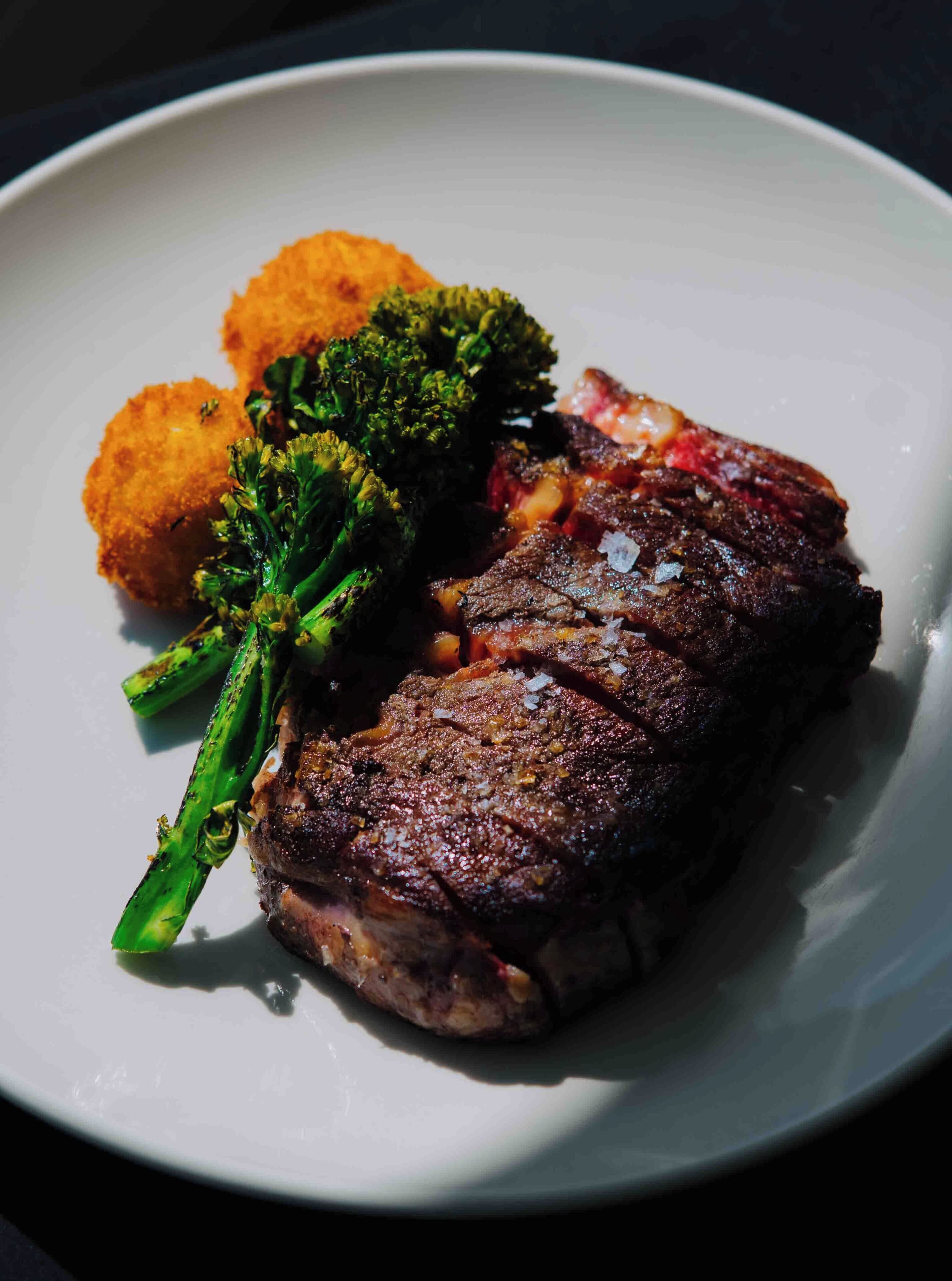 Une assiette contenant un steak, des brocolis et, en accompagnement, ce qui semble être un plat à base de pommes de terre.