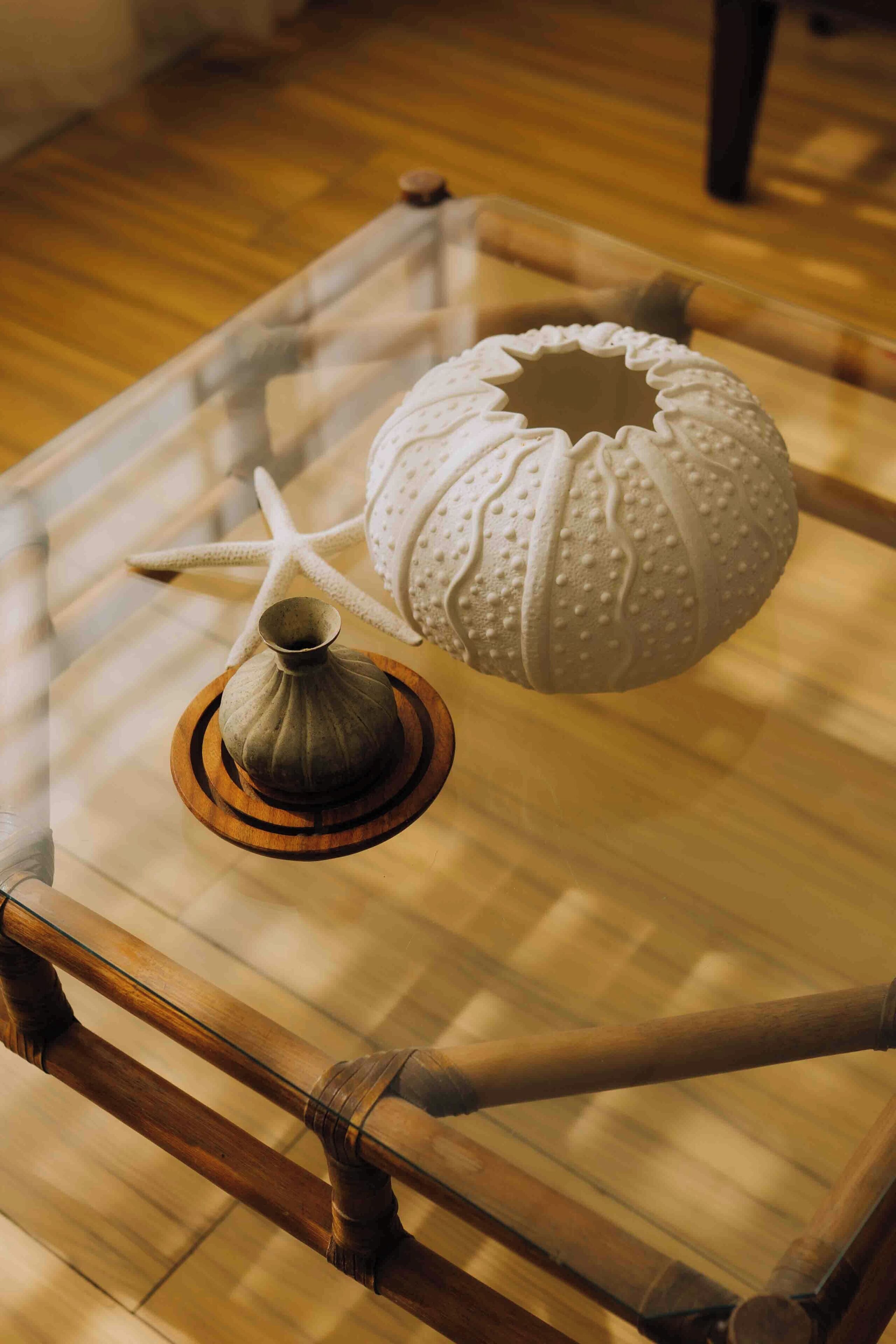 A glass-top table with a decorative vase and a textured spherical object.