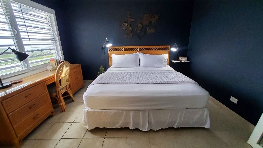 Ein Schlafzimmer mit Bett, Holztisch, Stuhl und Nachttischlampen.