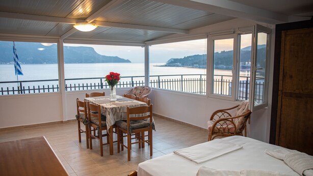 A balcony with a wooden table, chairs, and a bed. - White Heaven Marina View. Studio Near the Lakki Port. (Lakki)