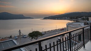 A coastal view with a road, parked cars, and a calm sea during sunset. - White Heaven Marina View. Studio Near the Lakki Port. (Lakki)
