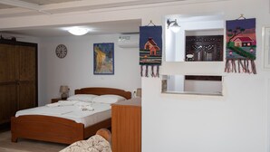 A bedroom with a wooden bed, a nightstand, a wall clock, and a painting. - White Heaven Marina View. Studio Near the Lakki Port. (Lakki)