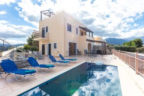 Un espace piscine avec des chaises longues et un bâtiment doté d’un balcon.