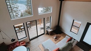 A spacious living area with a large window overlooking a deck, a ceiling fan, and a cozy seating area with a sofa and a small table.