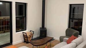 A modern living room with a large gray sofa, a wooden coffee table, and a black fireplace.