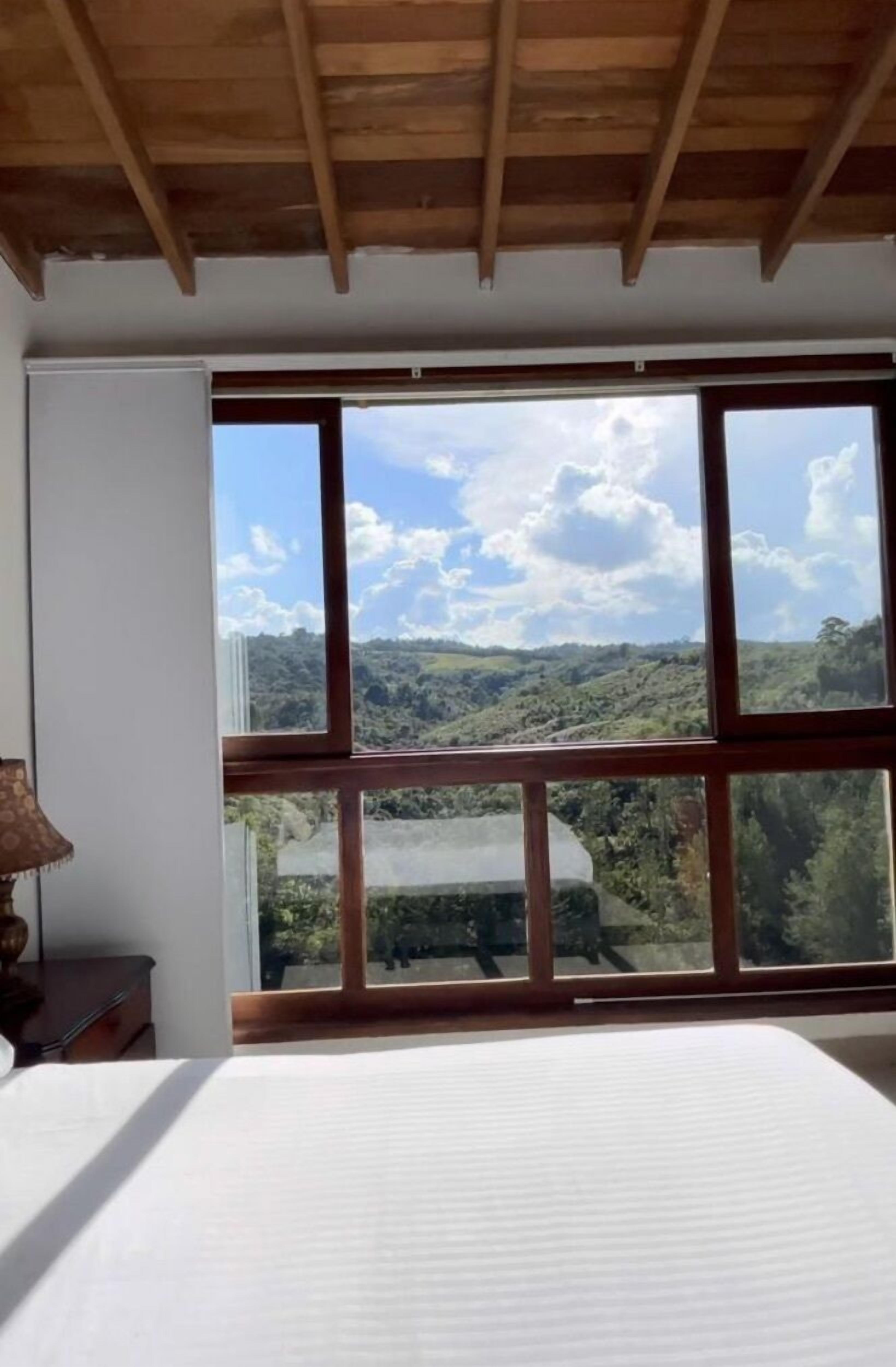 Een slaapkamer met een groot raam dat uitzicht biedt op een heuvelachtig landschap.