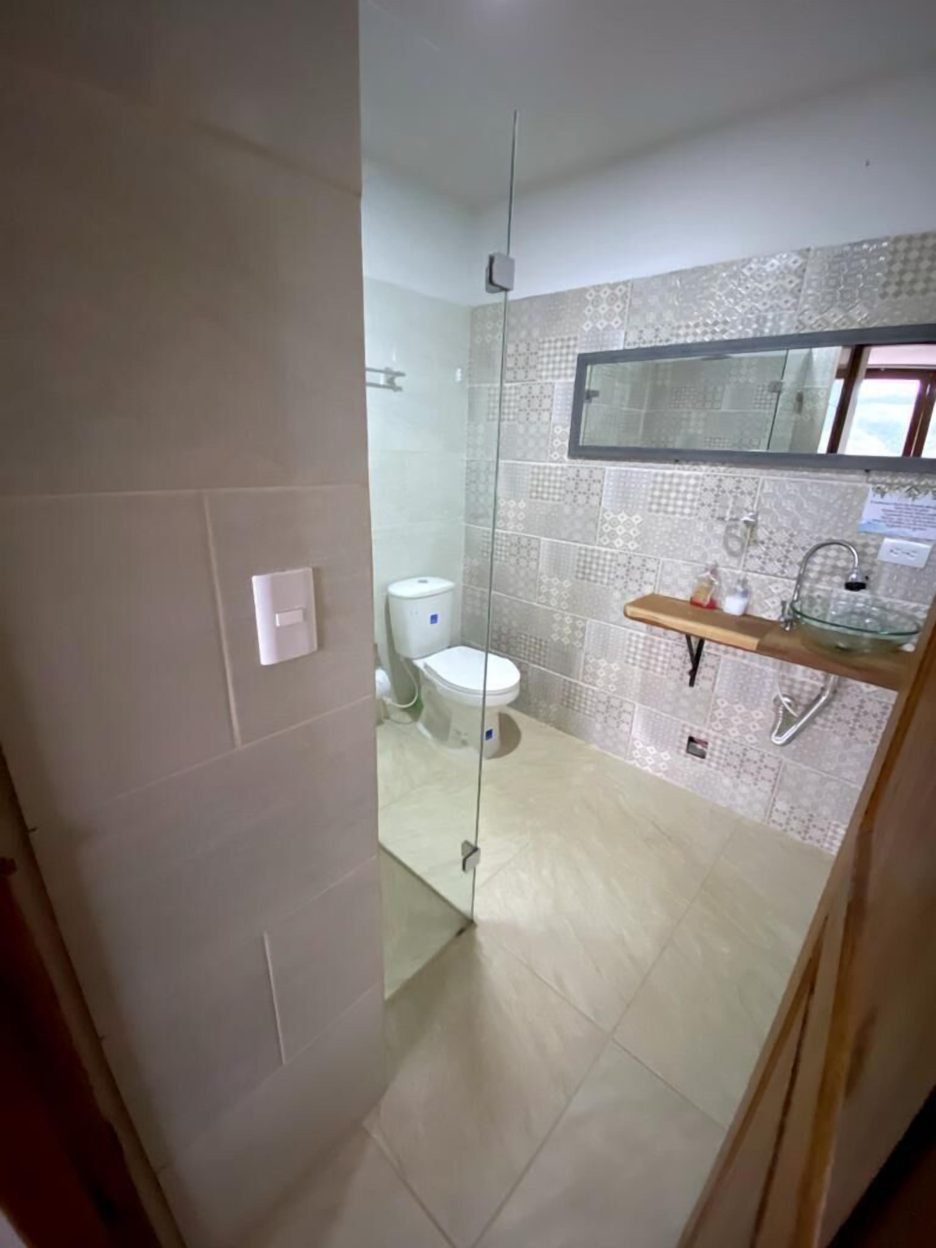A bathroom with a toilet, a glass shower enclosure, and a tiled backsplash.