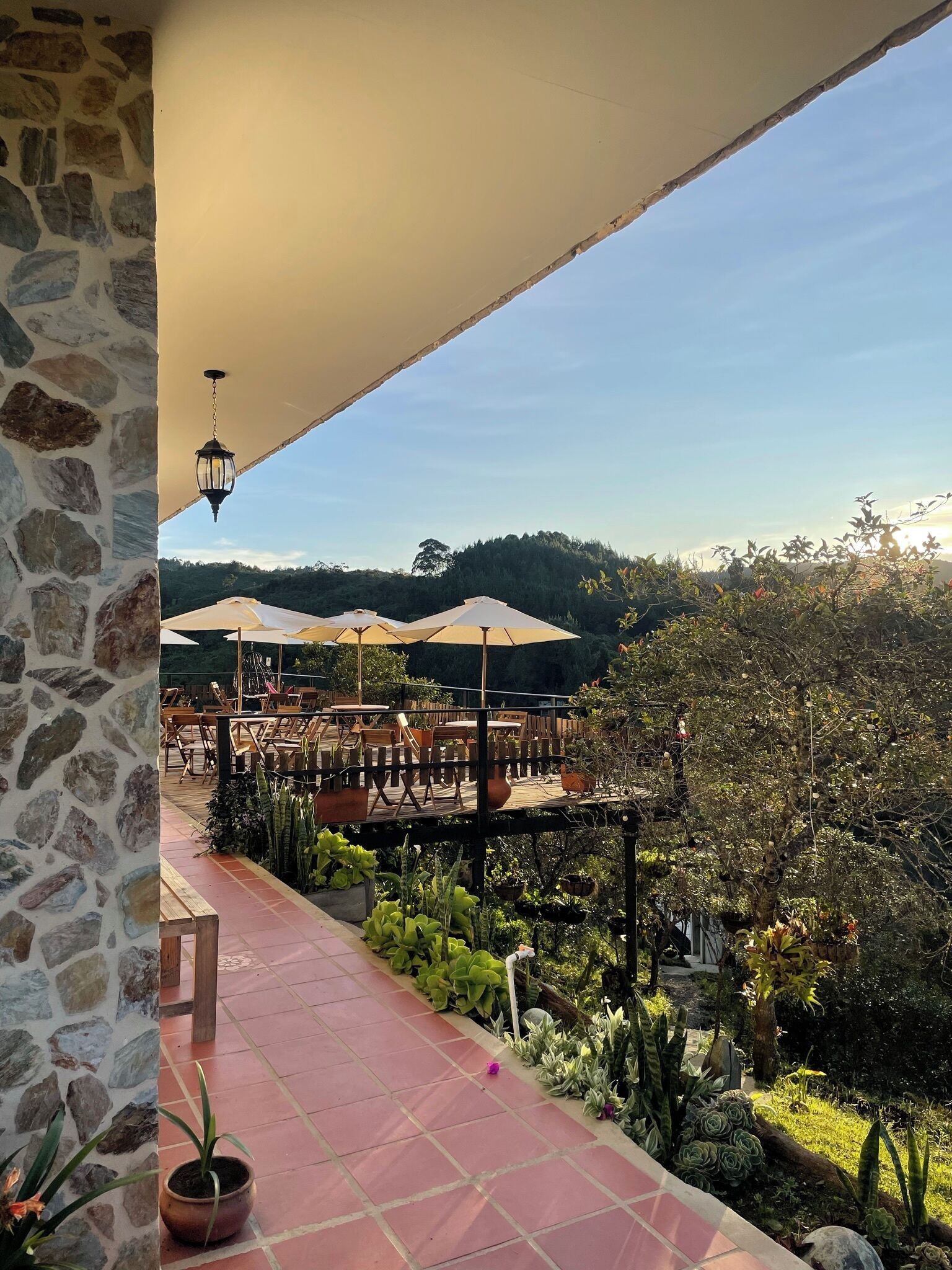 Una terraza con muros de piedra, asientos exteriores y plantas en macetas.
