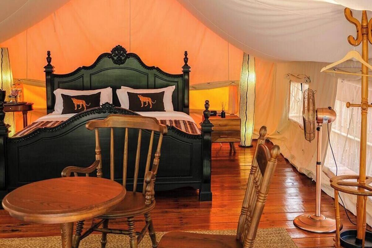 A bedroom with a large bed, a wooden chair, a table, and a lamp.